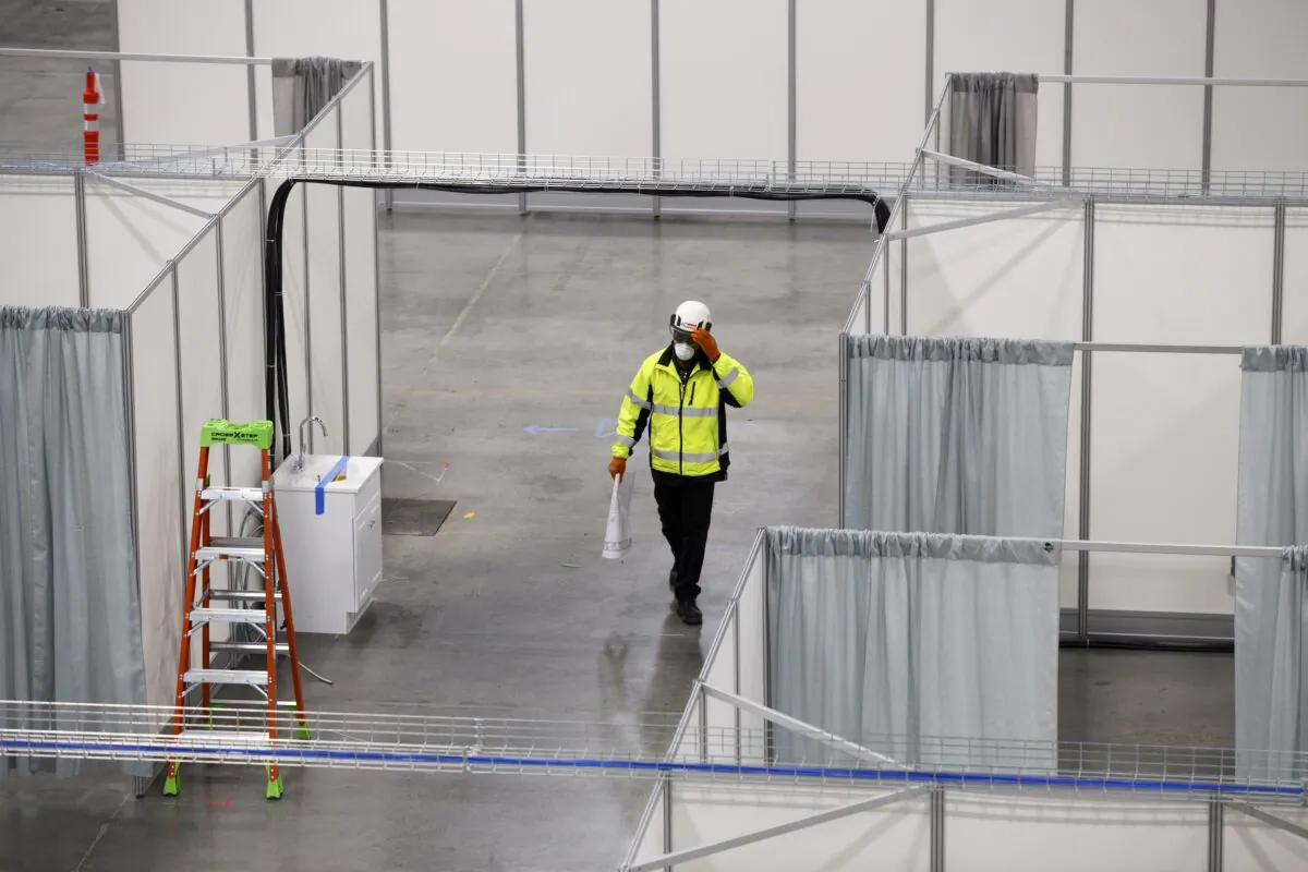 A worker walks by rows of beds in a convention hall at the Suburban Collection Showplace, which is being converted into a field hospital to treat CCP virus patients in Novi, Michigan on April 11, 2020. (Elaine Cromie/Getty Images)