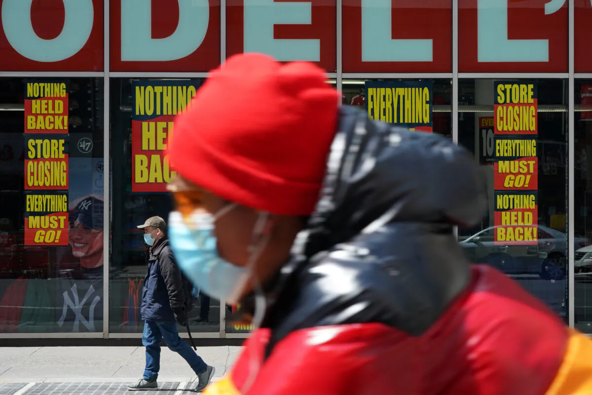A man wears a mask as he rides past a closed Modell's in New York City on April 15, 2020. (Reuters/Bryan R Smith)