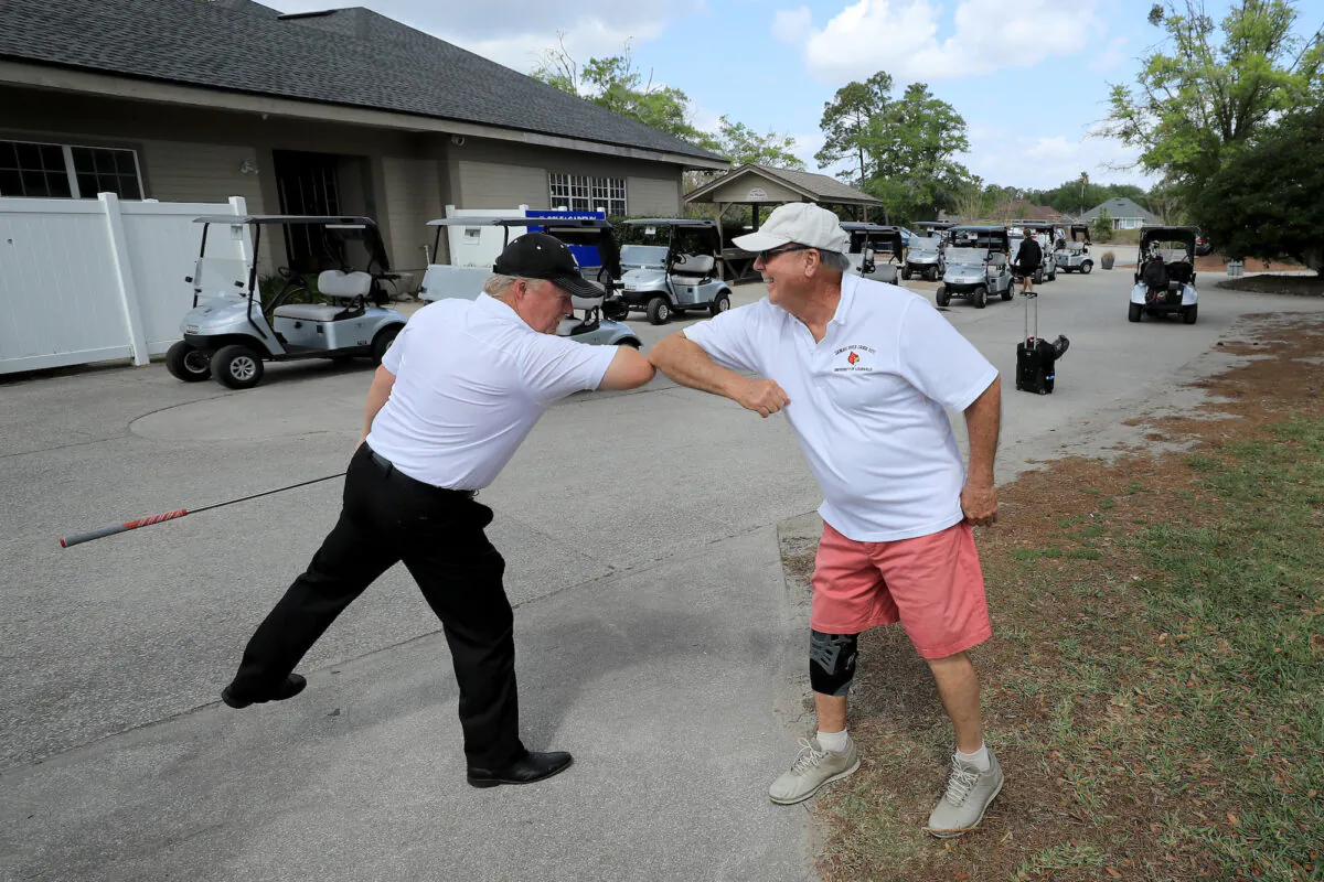 Golfers bump elbows at Windsor Parke Golf Club in Jacksonville Beach, Florida, on March 25, 2020. (Sam Greenwood/Getty Images)