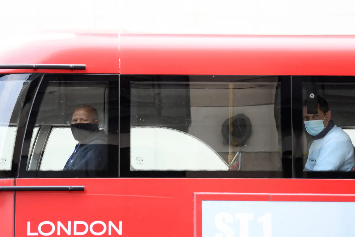 Two passengers wearing masks are seen on a bus in London, UK, on April 17, 2020. (Reuters/Toby Melville)