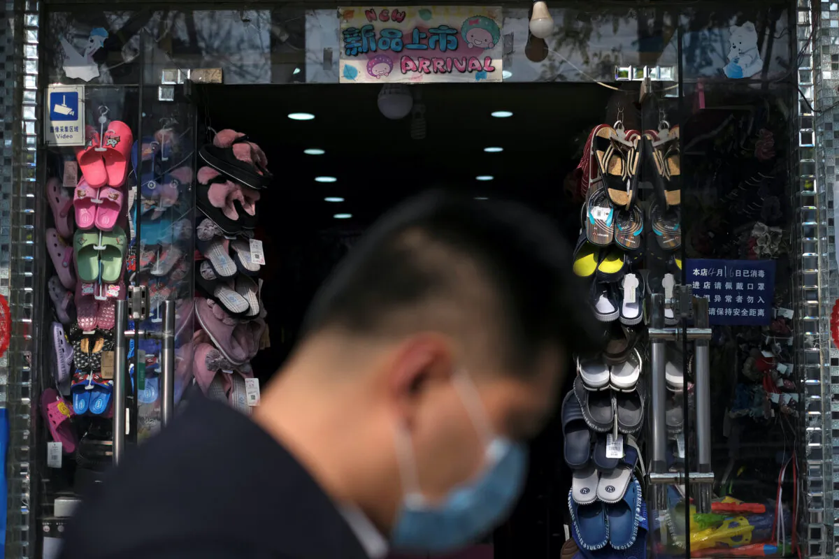 A man wearing a face mask walks past a store in Beijing, following an outbreak of the COVID-19 disease, in China on April 17, 2020. (Carlos Garcia Rawlins/Reuters)