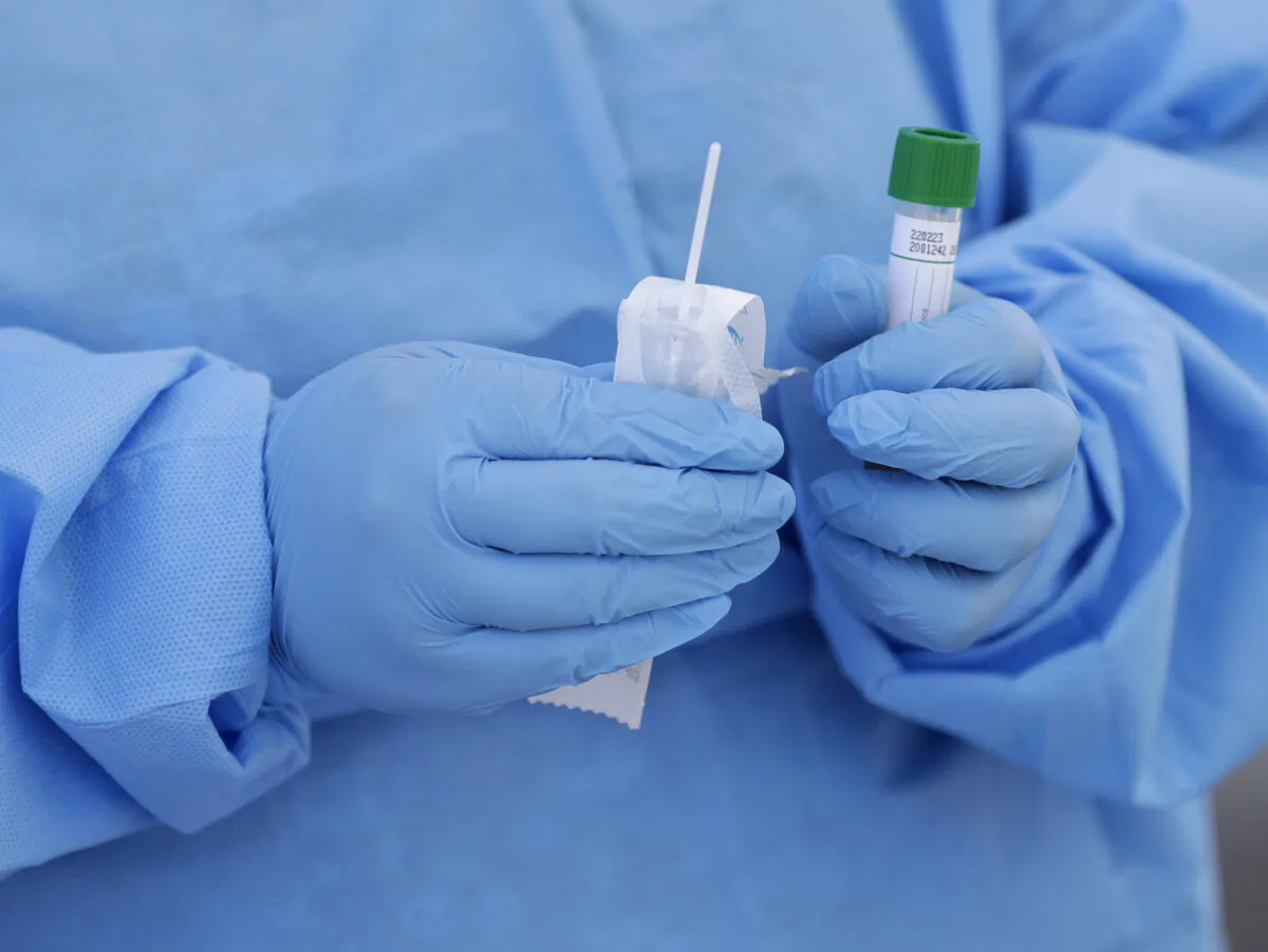 A health care worker prepares to collect a sample to test for COVID-19 at a drive-through testing site at a community health center in Miami, in a March 20, 2020, file photo. (Wilfredo Lee/AP Photo)