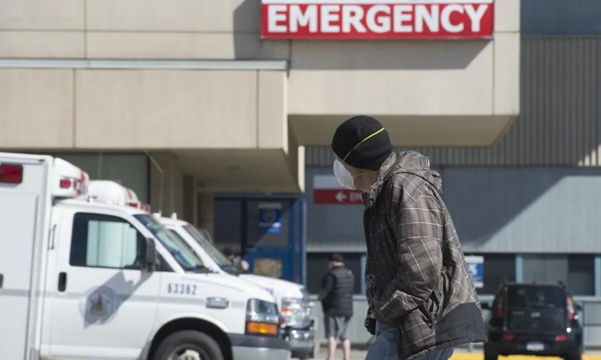 A man wears a mask as he walks past the emergency department of the Royal Columbian Hospital in New Westminster, B.C., Canada, on April 3, 2020. (Jonathan Hayward/The Canadian Press)