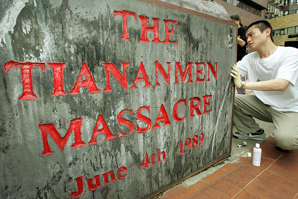 A Hong Kong University student cleans a plaque on May 4, 2005, below the "The Pillar of Shame," a monument constructed to honor the dead and to shame the Chinese Communist Party that refused to apologize for the Tiananmen Square massacre—the killing of students on June 4, 1989, in Beijing's Tiananmen Square. (MIKE CLARKE/AFP via Getty Images)