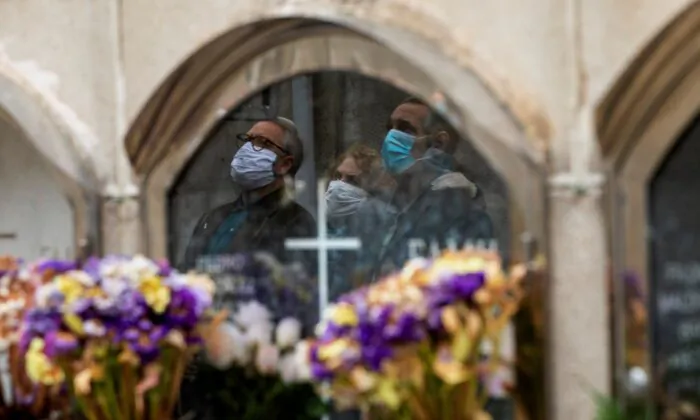 A woman next to her husband (L), and her brother (R), attend the funeral of their mother who died from the CCP virus at the Poble Nou cemetery in Barcelona, Spain, April 18, 2020. (Emilio Morenatti/AP Photo)