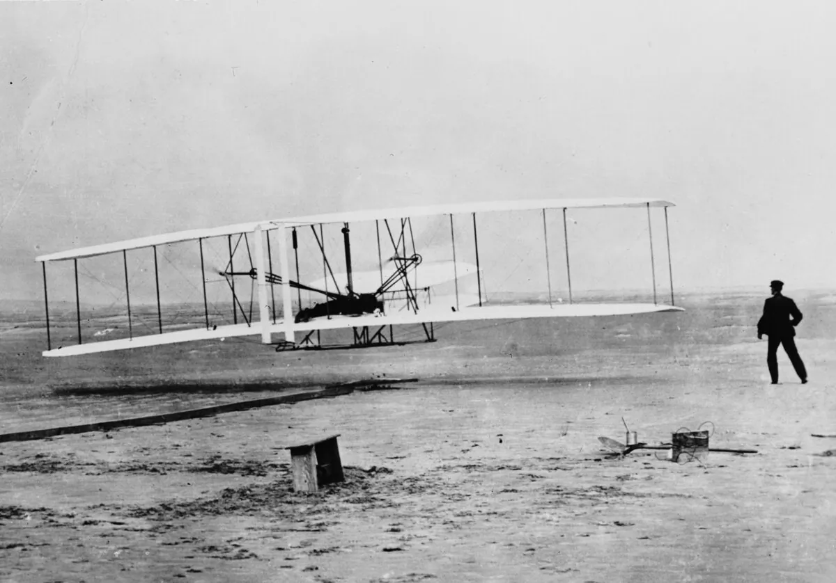 Orville Wright flying a Wright glider at Kill Devil Hills, near Kitty Hawk, North Carolina. The flight was officially the first sustained, controlled flight by a heavier-than-air craft. Wilbur Wright runs alongside his brother. (Fox Photos/Getty Images)