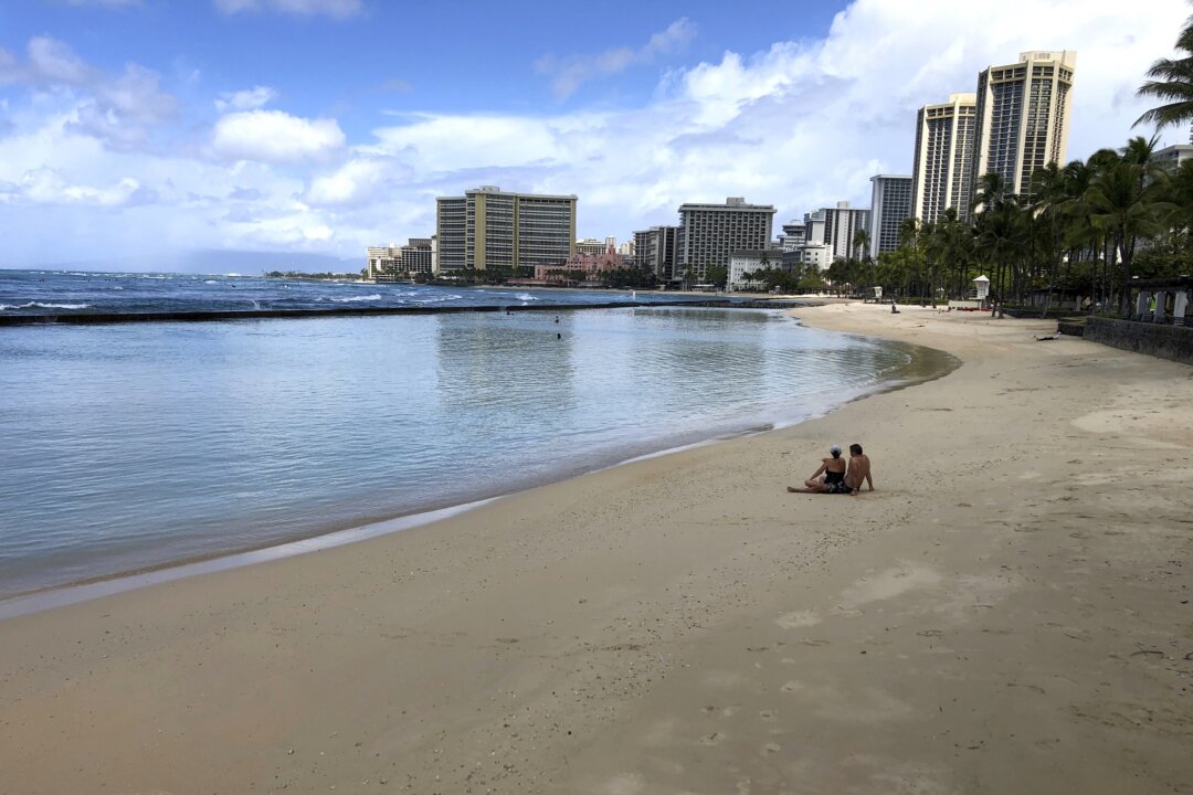 A couple sits on an empty section of Waikiki Beach in Honolulu on March 28, 2020. (Caleb Jones/AP Photo)