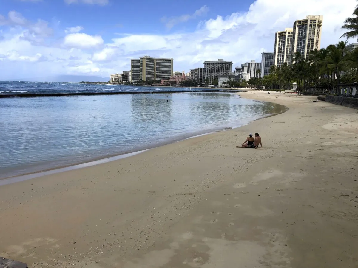 A couple sits on an empty section of Waikiki Beach in Honolulu on March 28, 2020. (Caleb Jones/AP Photo)