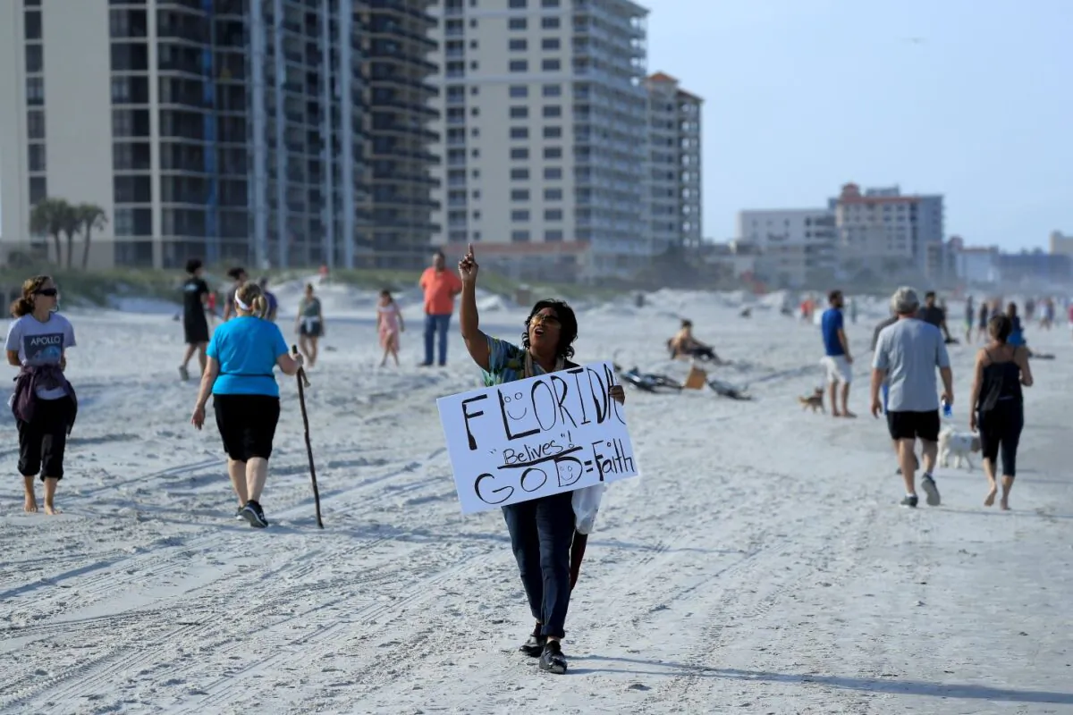 A person carries a sign at the beach in Jacksonville Beach, Florida, on April 17, 2020. (Sam Greenwood/Getty Images)