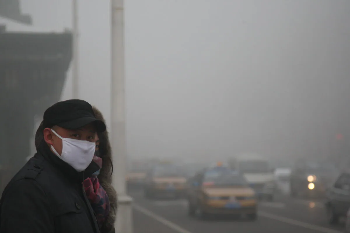 Pedestrians walk along a road as heavy smog engulfs the city in Harbin, China on Dec. 3, 2013. (Getty Images)