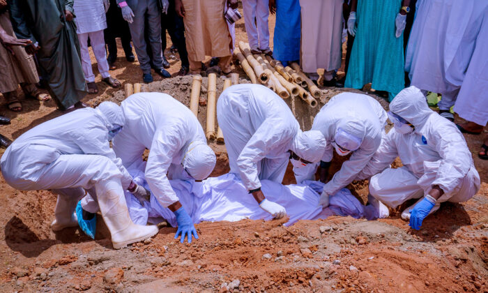 Men wearing protective gear bury the body of Nigerian president's chief of staff, Abba Kyari, who died on Friday after contracting COVID-19, at Gudu Cemetery in Abuja, Nigeria April 18, 2020. (Nigeria Presidency/Handout via Reuters.)