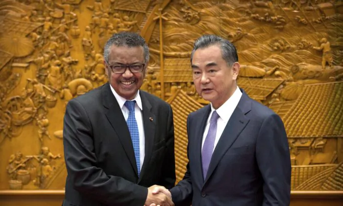 WHO Director-General Tedros Adhanom Ghebreyesus shakes hands with Chinese Foreign Minister Wang Yi as he arrives for a meeting at the Ministry of Foreign Affairs in Beijing, on July 17, 2018. (AP Photo/Mark Schiefelbein, Pool)