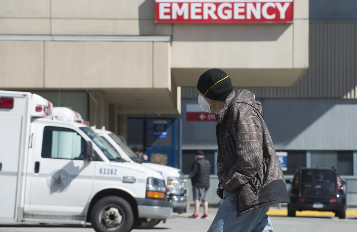 A man wearing a protective face mask walks past the emergency department of the Royal Columbian Hospital in New Westminster, B.C., on April 3, 2020. (The Canadian Press/Jonathan Hayward)
