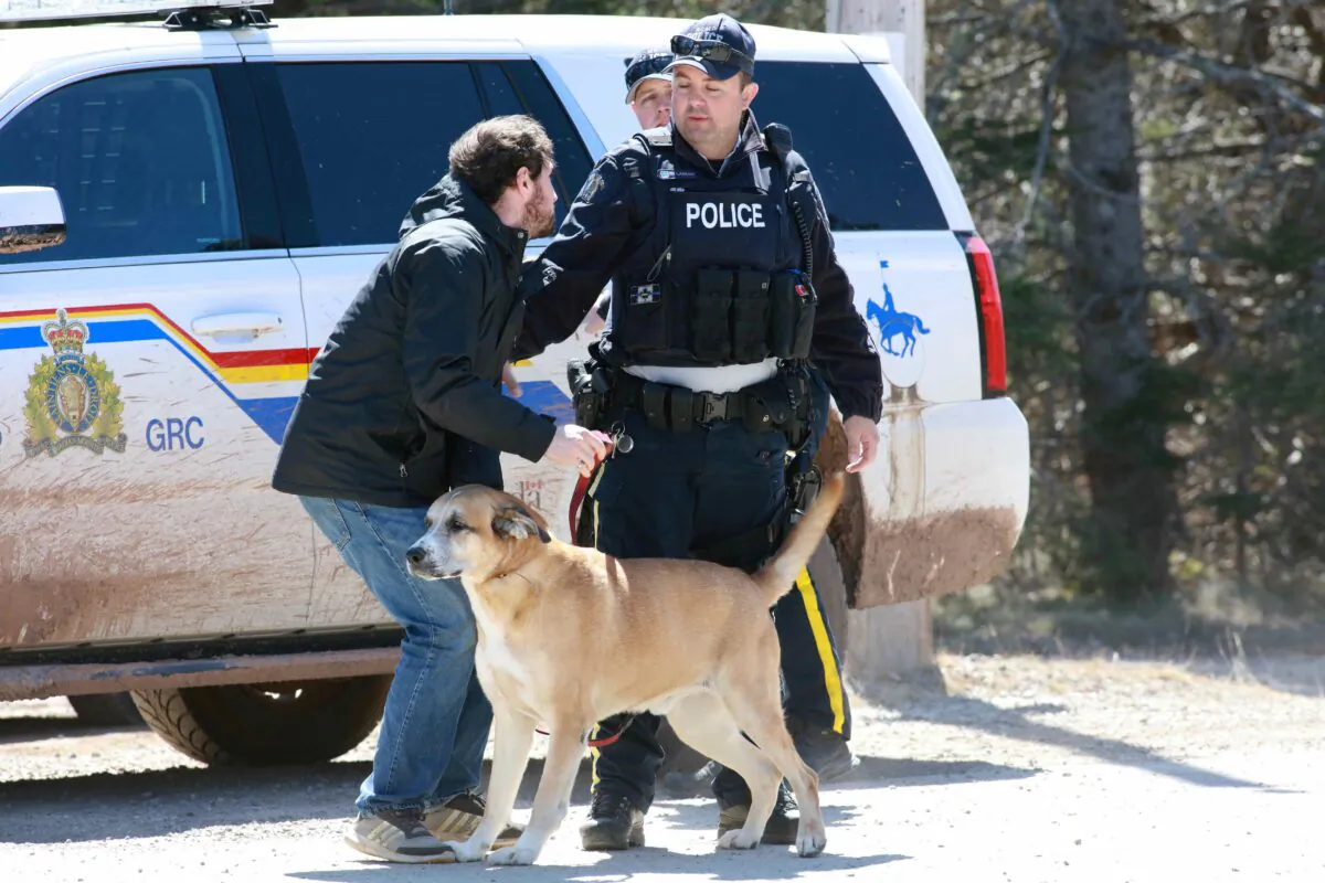 A Royal Canadian Mounted Police (RCMP) officer returns a dog to an individual since the road is shut down after a manhunt for Gabriel Wortman, who they describe as a shooter of multiple victims, in Portapique, Nova Scotia, Canada, on April 19, 2020. (John Morris/Reuters)