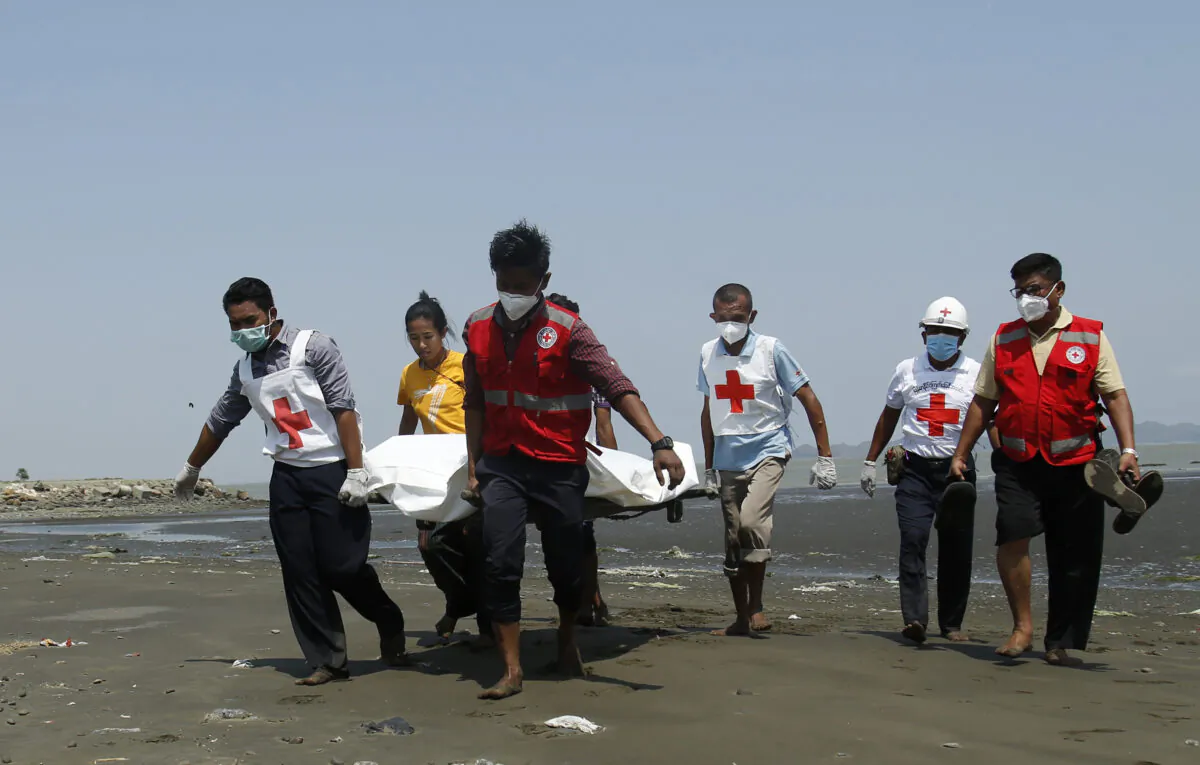 Members of the Myanmar Red Cross carry a dead body of a driver from a boat in Sittwe, Rakhine State, killed while delivering test kits for the CCP virus, in Burma, on April 21, 2020. (STR / AFP via Getty Images)