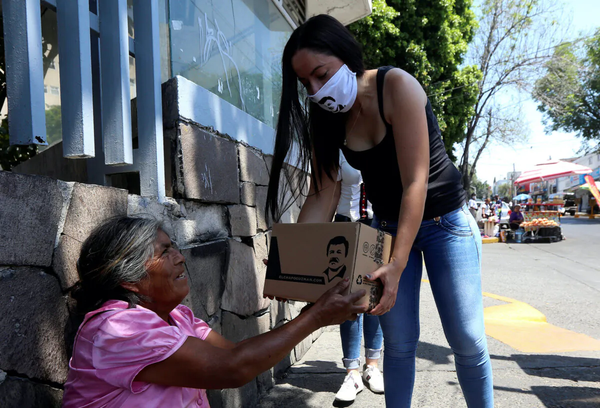 An employee of the clothing brand "El Chapo 701," owned by Alejandrina Gisselle Guzman, daughter of the convicted drug kingpin Joaquin "El Chapo" Guzman, hands out a box with food, face masks and hand sanitizers to an elderly woman as part of a campaign to help cash-strapped elderly people during the COVID-19 disease outbreak, in Guadalajara, Mexico, April 16, 2020.  (Fernando Carranza/Reuters File)