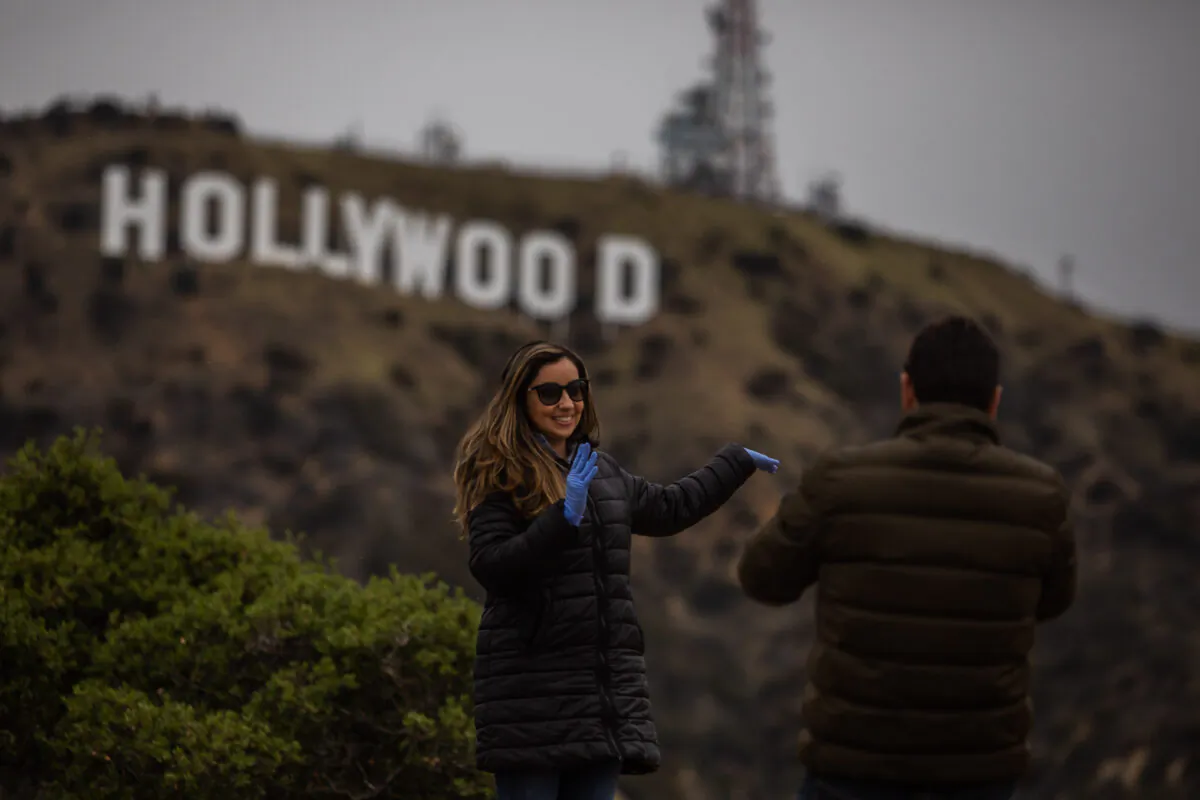 A woman poses below the Hollywood sign in Hollywood, Calif., on March 22, 2020. (Apu Gomes/AFP via Getty Images)