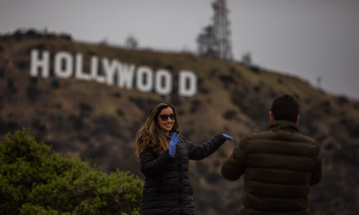 A woman poses below the Hollywood sign in Hollywood, Calif., on March 22, 2020. (Apu Gomes/AFP via Getty Images)
