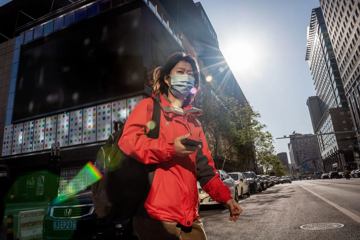 A woman wearing a face mask amid concerns over the CCP virus crosses a street in Beijing on April 22, 2020. (Nicolas Asfouri/AFP via Getty Images)
