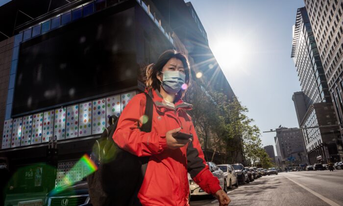 A woman wearing a face mask amid concerns over the CCP virus crosses a street in Beijing on April 22, 2020. (Nicolas Asfouri/AFP via Getty Images)