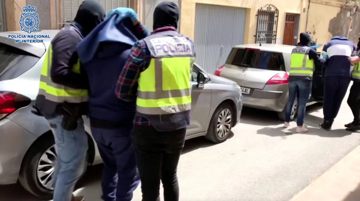 Men, with heads covered with towels, are led out of a building to cars, in Almeria, Spain April 21, 2020.(Spanish Police/Handout/Reuters)