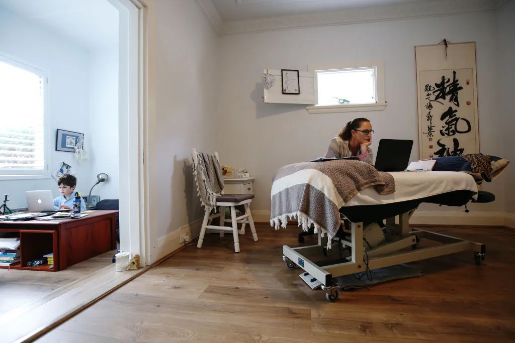 Phoenix Crawford does school work on a laptop while his mum Donna Eddy, a massage therapist and acupuncturist, replies to client emails in Sydney, Australia on April 09, 2020. (Brendon Thorne/Getty Images)