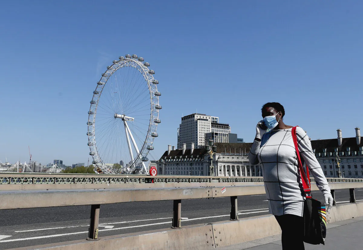 A woman wearing a mask to protect against the CCP virus walks over Westminster Bridge in London, on April 22, 2020. (Frank Augstein/AP)