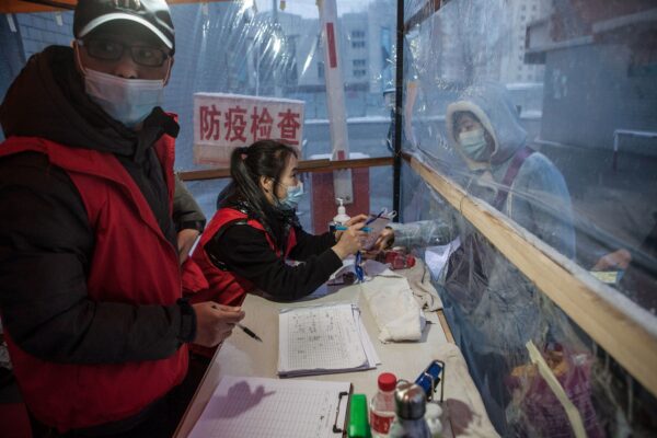 A staff member (C) checking the body temperature