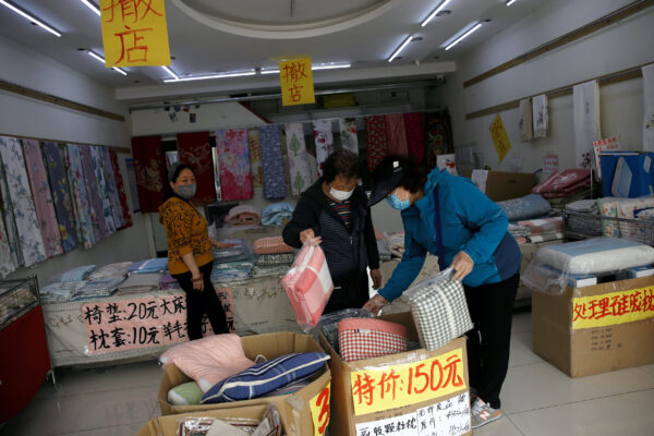 Customers wearing face masks shop bed linen under business closure notices inside a home linen store whose business has been struggling since the coronavirus disease (COVID-19) outbreak, in Beijing