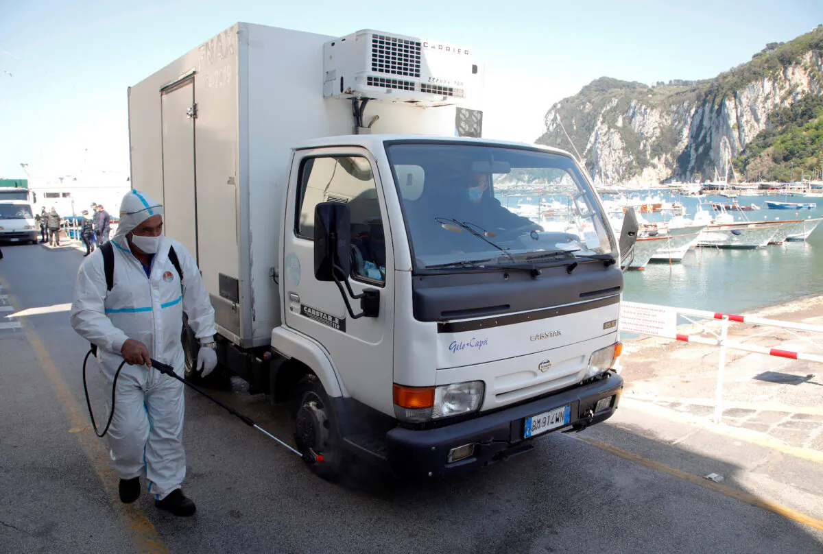 A worker wearing protective clothing disinfects a vehicle after disembarking from a ferry in Capri, Italy, on April 24, 2020. (Ciro De Luca/Reuters)

