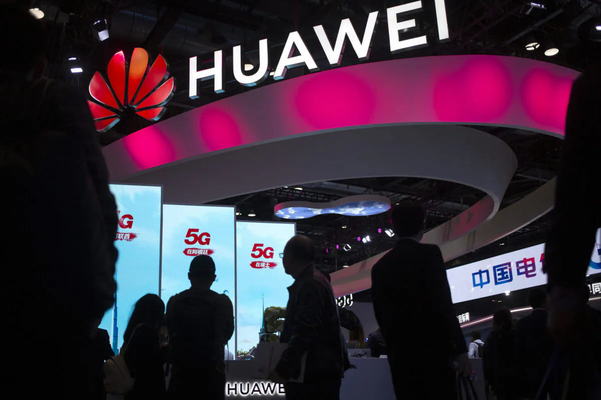 Attendees walk past a display for 5G services from Chinese technology firm Huawei at the PT Expo in Beijing, in this undated photo. (Mark Schiefelbein/AP Photo)