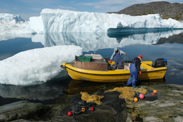 Inuit fishermen prepare a net as free-floating ice floats behind at the mouth of the Ilulissat Icefjord during unseasonably warm weather on July 30, 2019 near Ilulissat, Greenland. (Sean Gallup/Getty Images)
