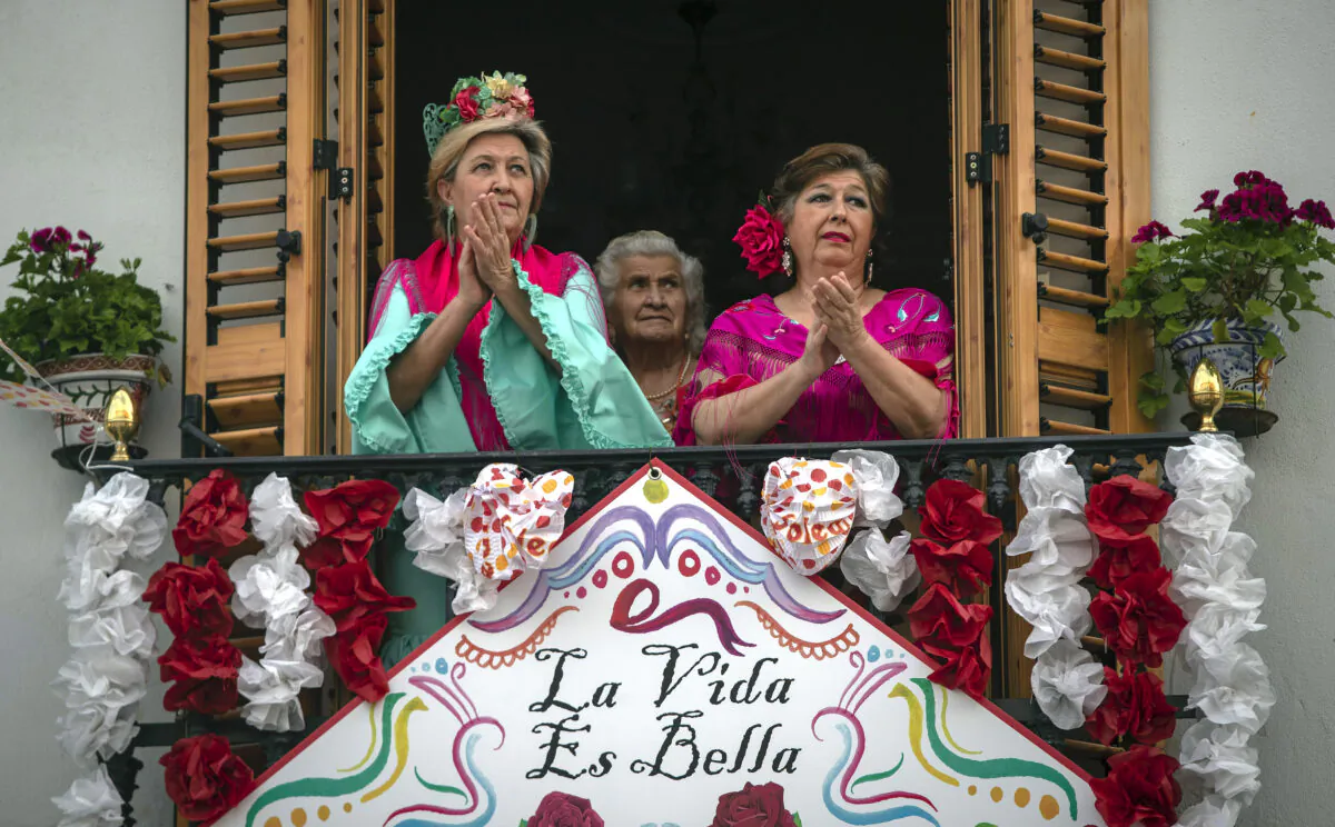 Women in traditional dress, applaud from their decorated balcony during the annual traditional April Fair in Seville, Spain on April 25, 2020. (Miguel Morenatti/AP Photo)