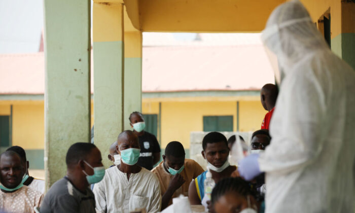 People wait as health workers prepare to take samples during a community CCP virus testing campaign in Abuja, Nigeria, on April 15, 2020. (Kola Sulaimon/AFP via Getty Images)