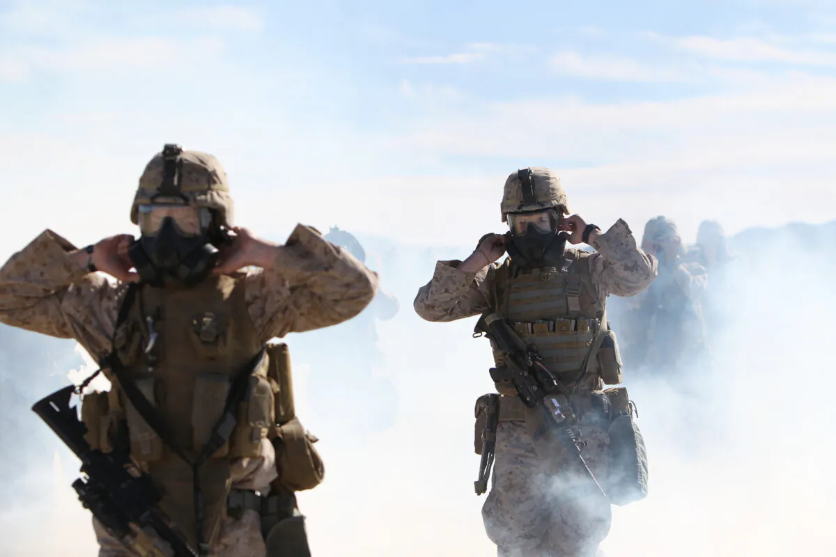 Marines and sailors with Company E, 2nd Battalion, 7th Marine Regiment, break the seals on their M50 Gas Masks in a cloud of CS gas during an outdoor gas exercise performed at range 210 Jan. 26, 2011. (Lance Cpl. Andrew Thorburn/DoD)