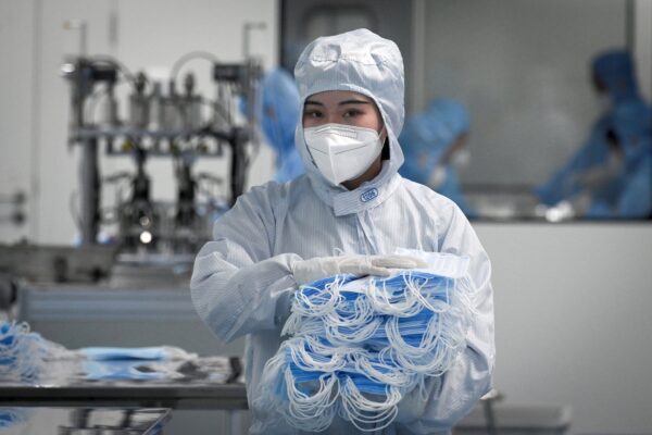 A worker wearing a protective suit holds masks