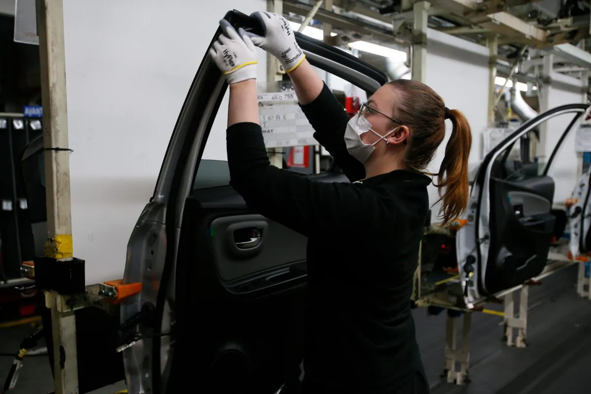 An employee wearing a face mask works on a door of a Yaris car at the Toyota car factory in Onnaing, northern France, on April 28, 2020. (Michel Spingler/AP Photo)