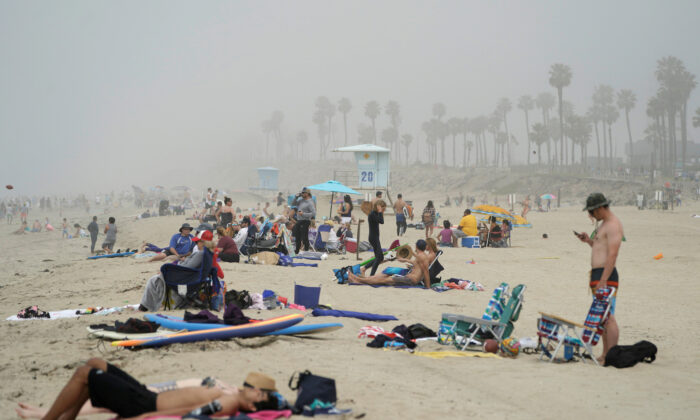 People sit in groups at Huntington City Beach during the outbreak of the CCP virus (COVID-19) in Huntington Beach, Calif., on April 25, 2020. (Kyle Grillot/Reuters)