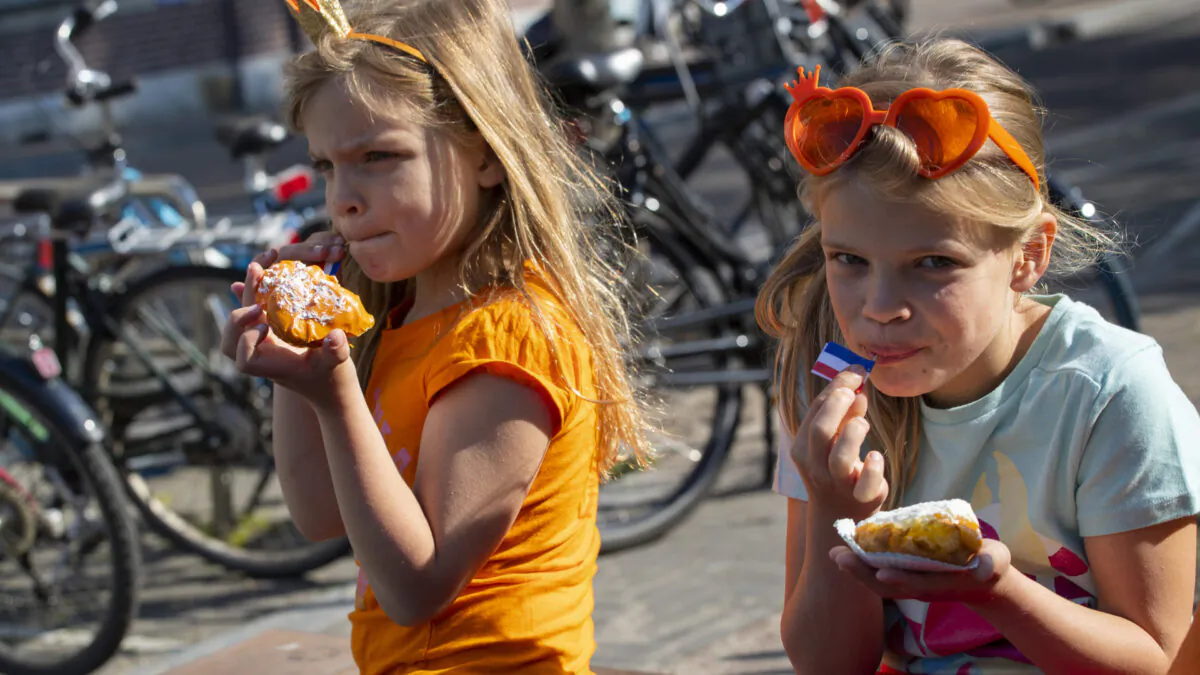 Two girls enjoy traditional King's Day pastry in Amsterdam, Netherlands, Monday, April 27, 2020. The Dutch national birthday party was a muted affair, dubbed King's Day at Home because of coronavirus restrictions, a far cry from the usual nationwide celebration with street parties. (Peter Dejong/AP)

