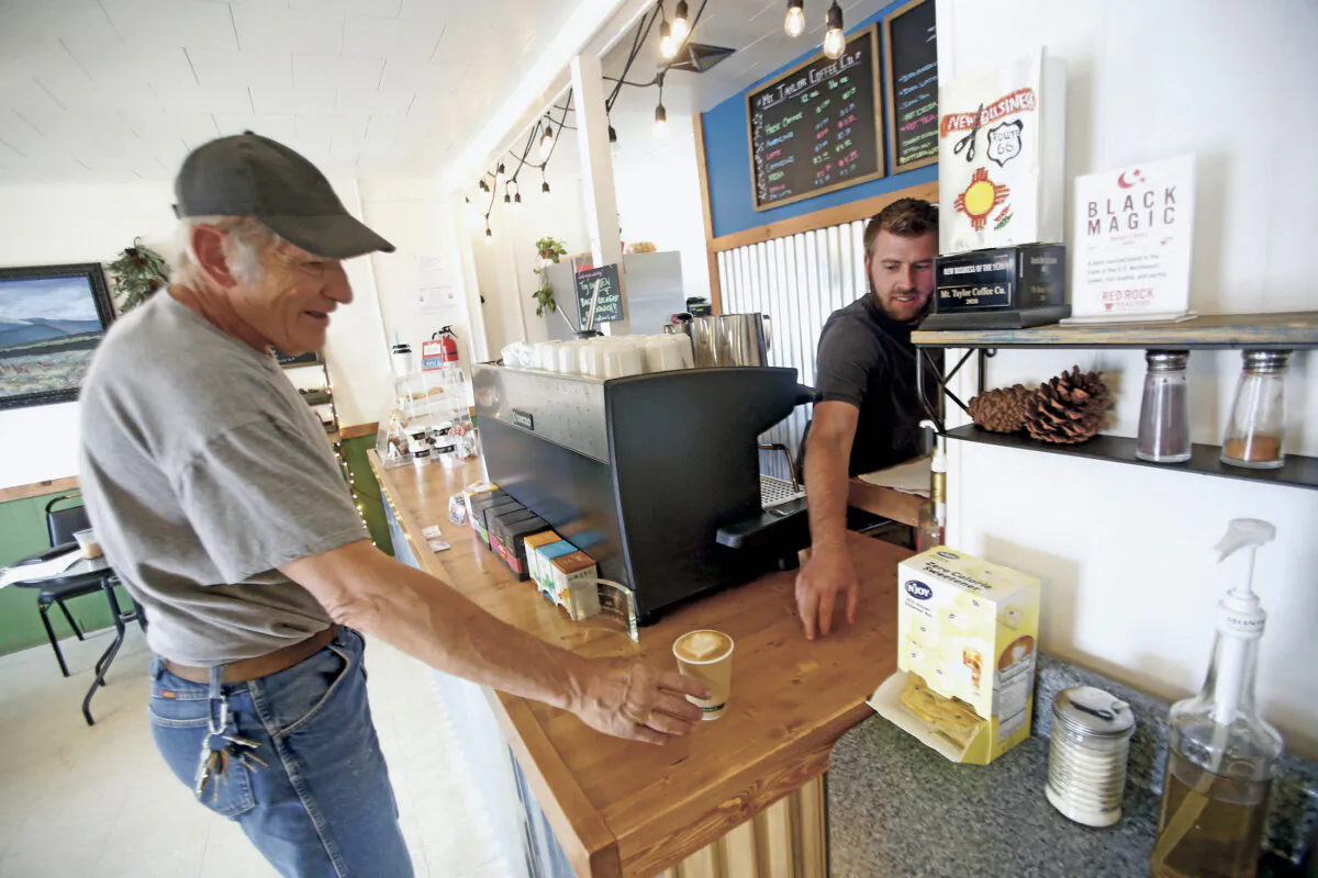 Jonathan Archibald, owner of Mt Taylor coffee, right sells a cup of coffee to Paul Jackson of grants in Grants, N.M. on April 27, 2020. Grants Mayor Martin Hicks in New Mexico opened the city's businesses back up with an executive order, defying the Governor's orders. (Luis Sánchez Saturno/Santa Fe New Mexican via AP)