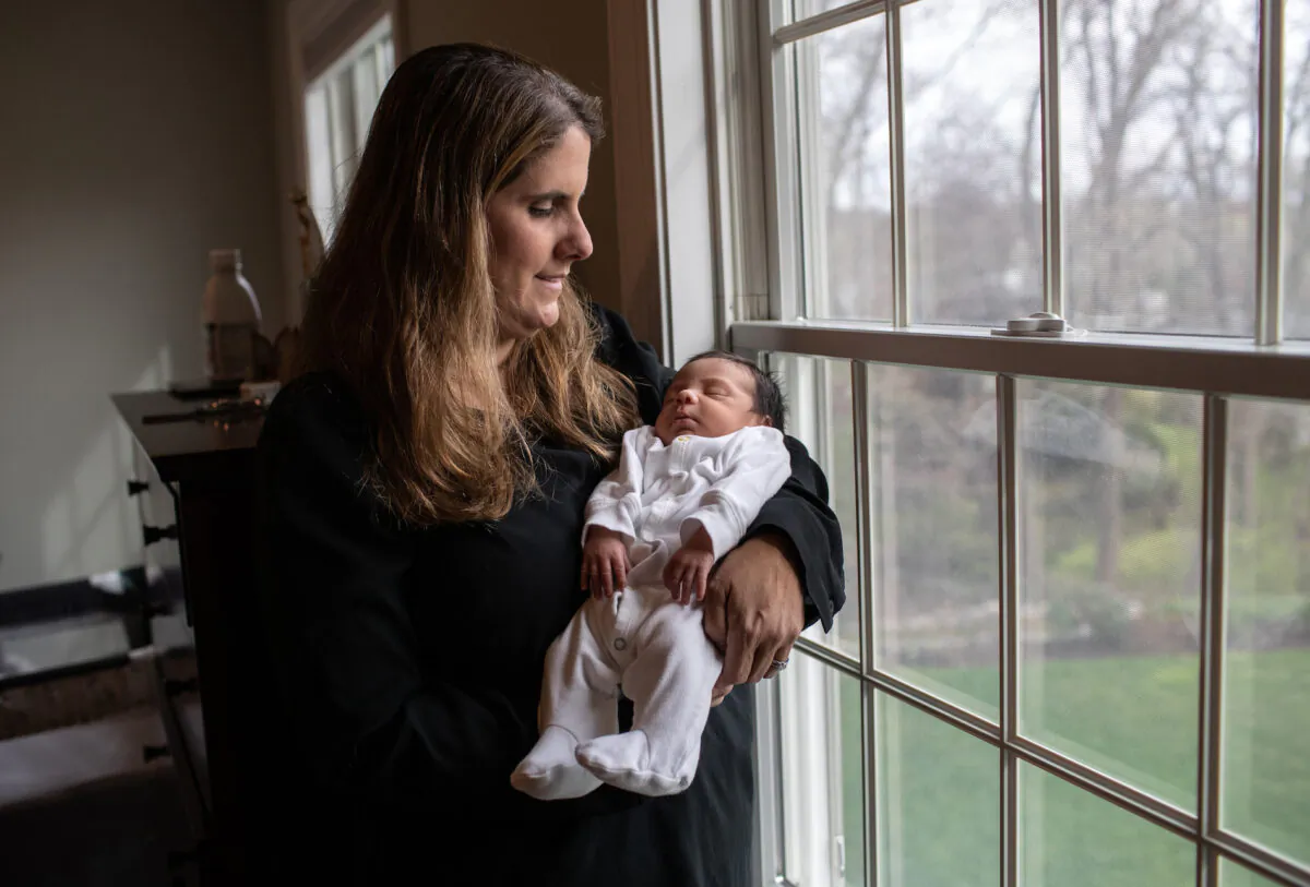 An elementary school teacher holds a baby in Stamford, Conn., on April 20, 2020. She became temporary guardian for the newborn, when the boy's immigrant mother Zully, a Guatemalan asylum seeker, went to a Stamford Hospital emergency room in labor. (John Moore/Getty Images)