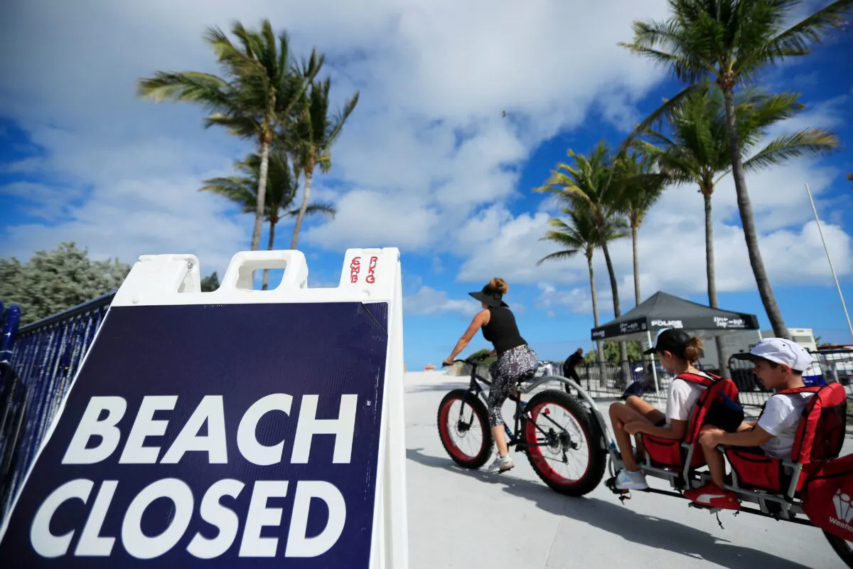 A cyclist with a trailer for children passes a "Beach Closed" sign in a file photo. (Cliff Hawkins/Getty Images)