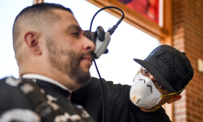The Bar.Ber.Shop owner Jose Oregel gives Jorge Orellana a haircut in Greeley, Colorado, on April 28, 2020. (Michael Ciaglo/Getty Images)