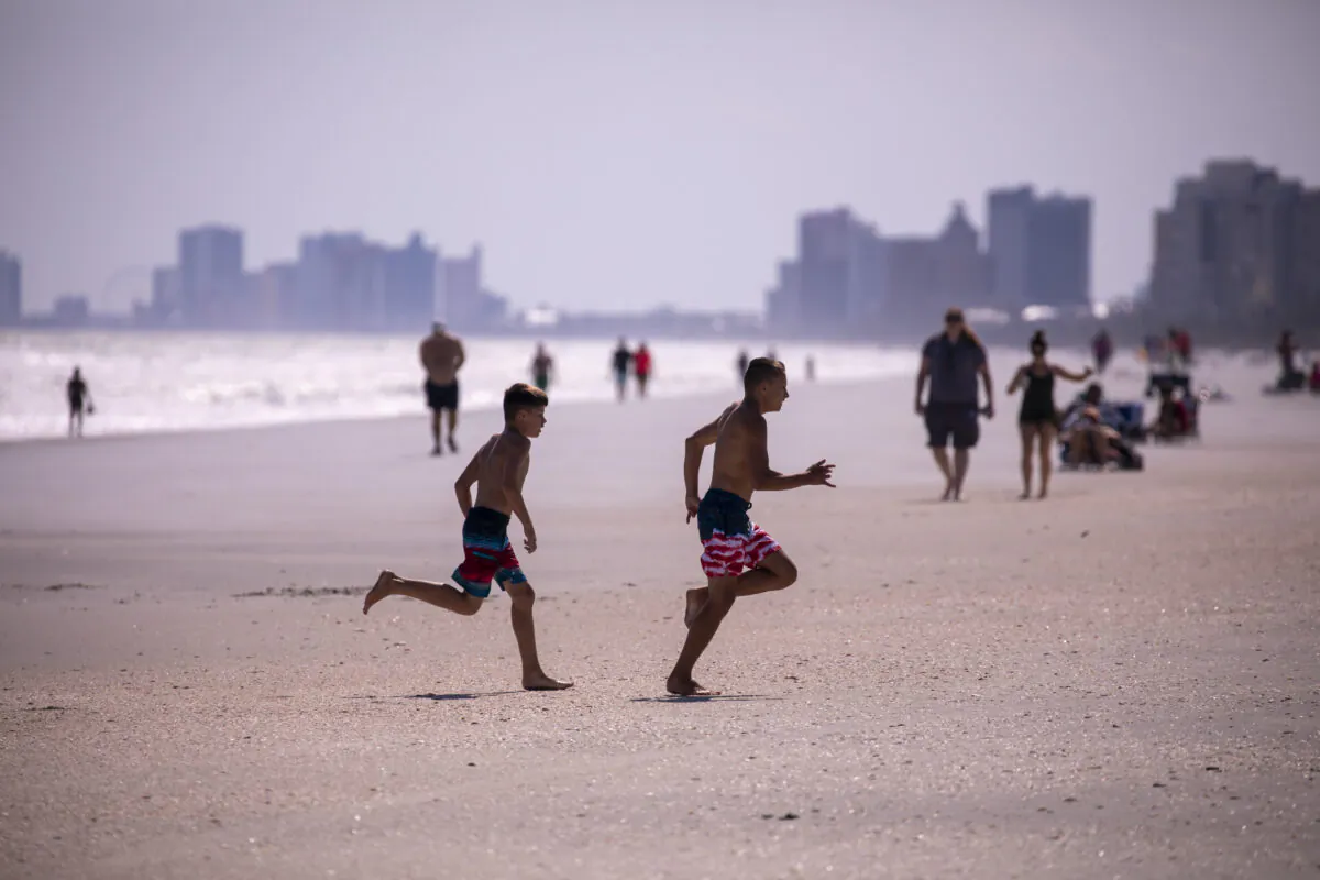 Groups of residents enjoy the beach in the Arcadian Shores section of Horry County, S.C., which reopened on April 21, 2020. (Jason Lee/The Sun News via AP)