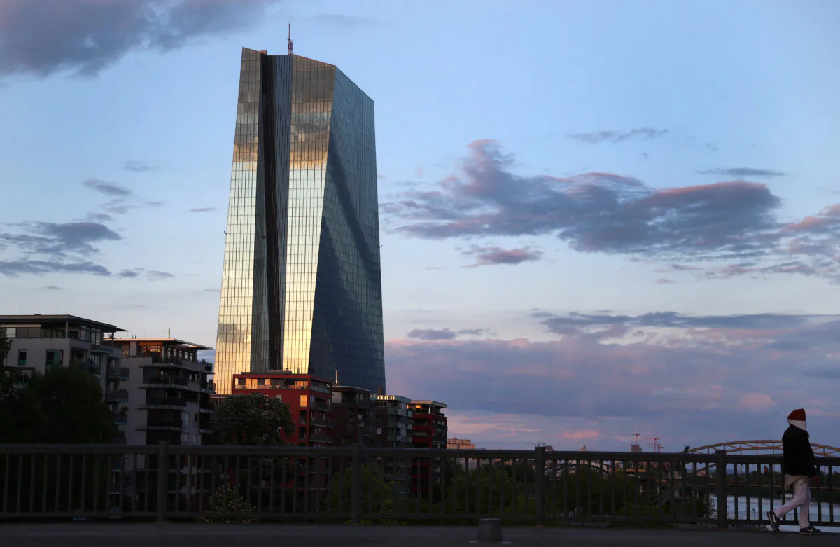A woman wears a protective mask while walking past the headquarters of the European Central Bank during sunset in Frankfurt, Germany, on April 29, 2020. (Kai Pfaffenbach/Reuters)