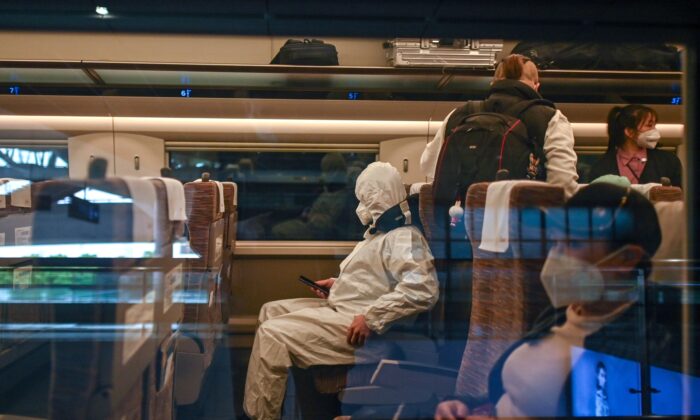 A man wearing a protective suit aboard a train heading to Shanghai at Wuhan Railway Station in Wuhan, China's central Hubei province, on April 21, 2020. (HECTOR RETAMAL/AFP via Getty Images)