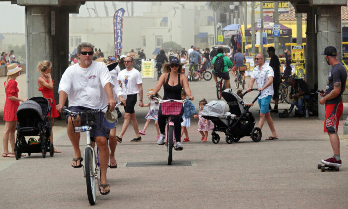 People ride bikes and walk on a path along the beach in Huntington Beach, Calif., on April 26, 2020. (Michael Heiman/Getty Images)
