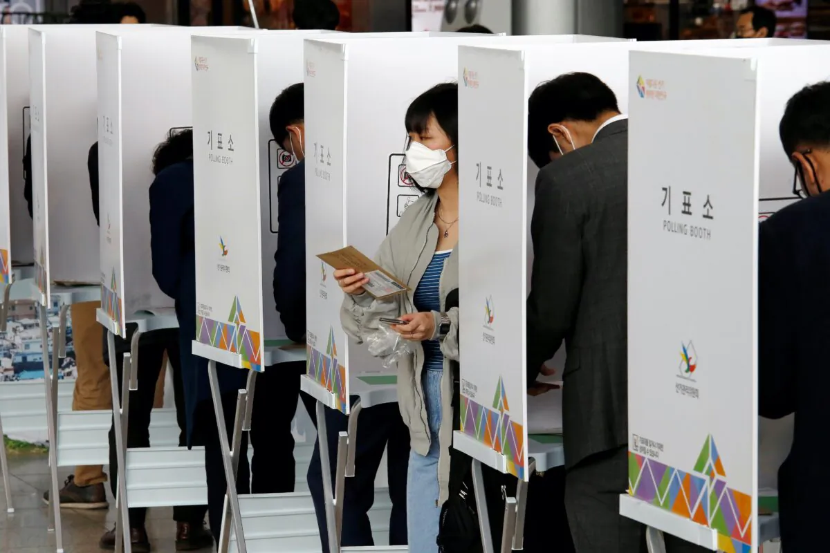 A woman leaves a voting booth to cast her absentee ballot for the parliamentary election at a polling station in Seoul, South Korea, on April 10, 2020. (Heo Ran/Reuters)