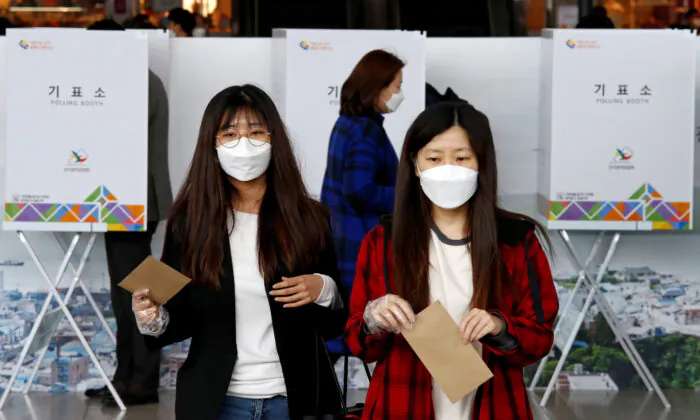 Women wearing masks and plastic gloves to prevent contracting the coronavirus cast their absentee ballots for the parliamentary election at a polling station in Seoul, South Korea, on April 10, 2020. (Heo Ran/Reuters)