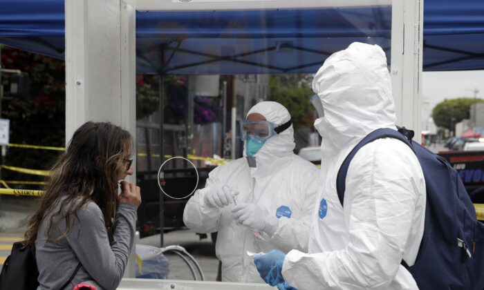 Members of the Los Angeles Fire Department wear protective equipment as they conduct a new CCP virus test on a woman in the Skid Row district in Los Angeles on April 20, 2020. (Marcio Jose Sanchez/AP Photo)